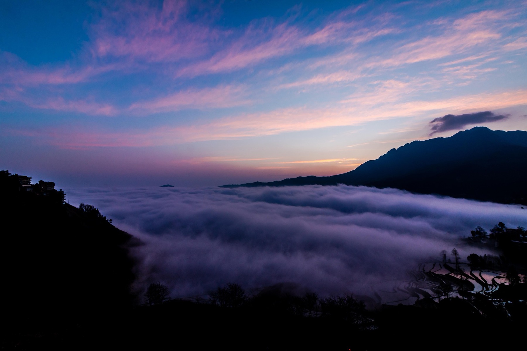 A sea of cloud filling a valley of rice terraces at dawn in Yunnan